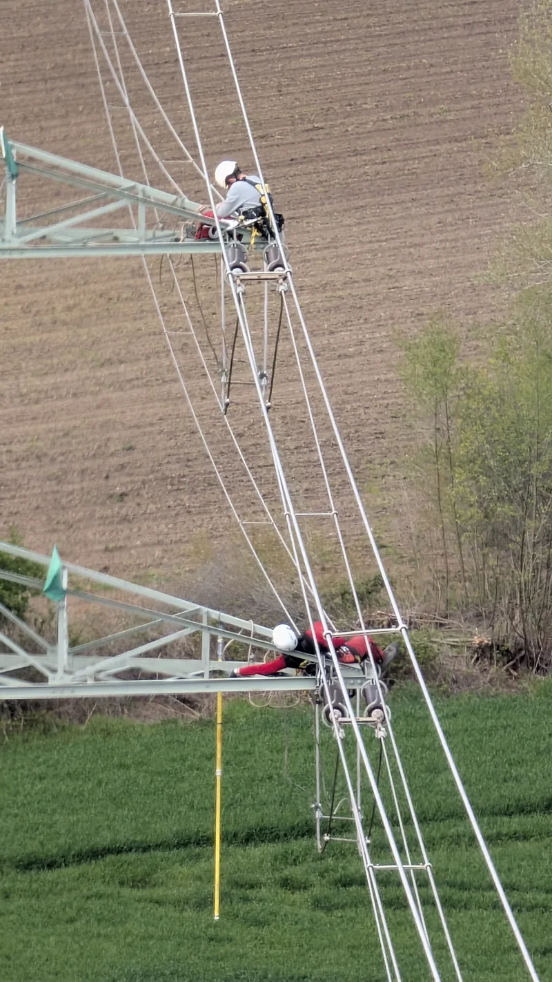 Pohled shora na pracovníky a konstrukci stožáru nad polem