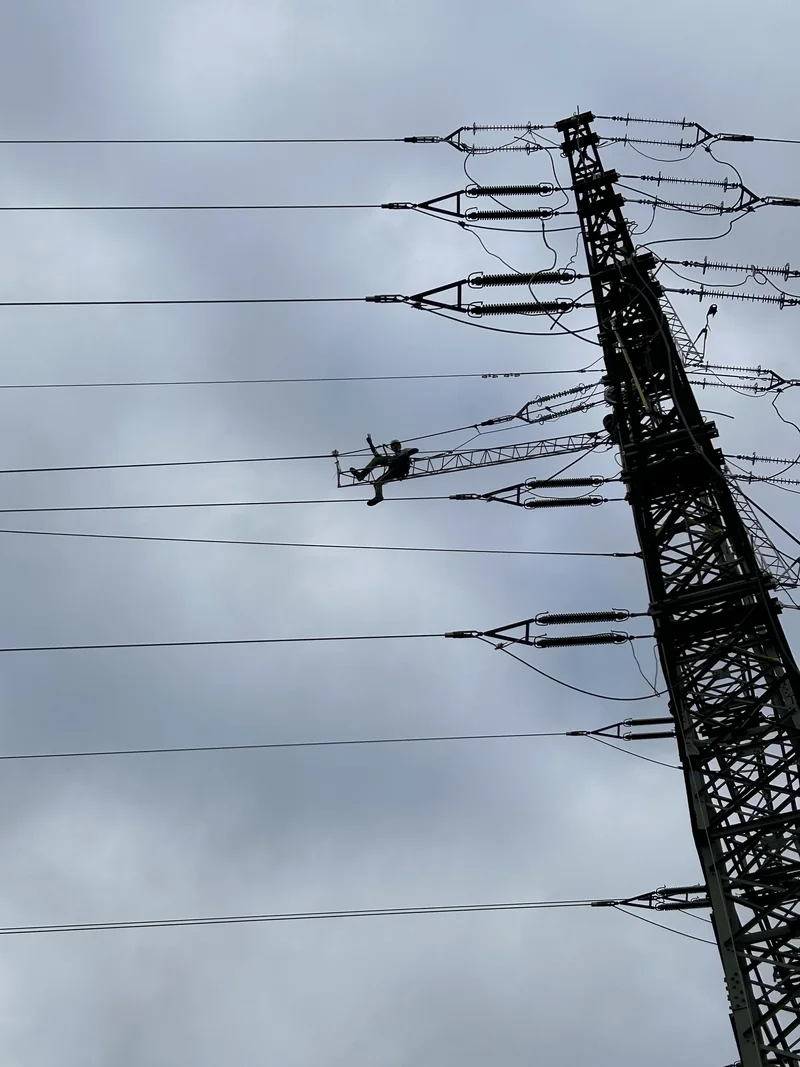 Pracovník na konstrukci elektrického vedení proti zatažené obloze
